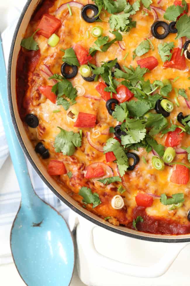 A white pot filled with Turkey Enchilada Casserole.