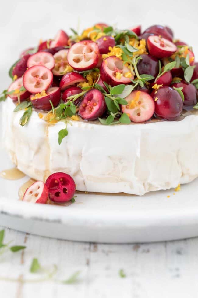 A brie round with cranberries and fresh thyme on top.