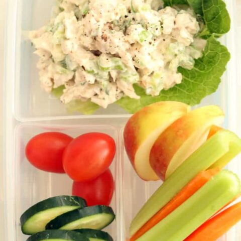A clear plastic lunch container filled with tarragon chicken salad and vegetables.