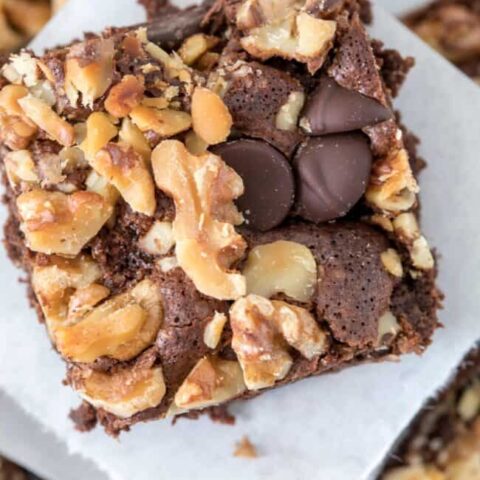 A gluten free brownie with almond flour sits on white parchment paper.