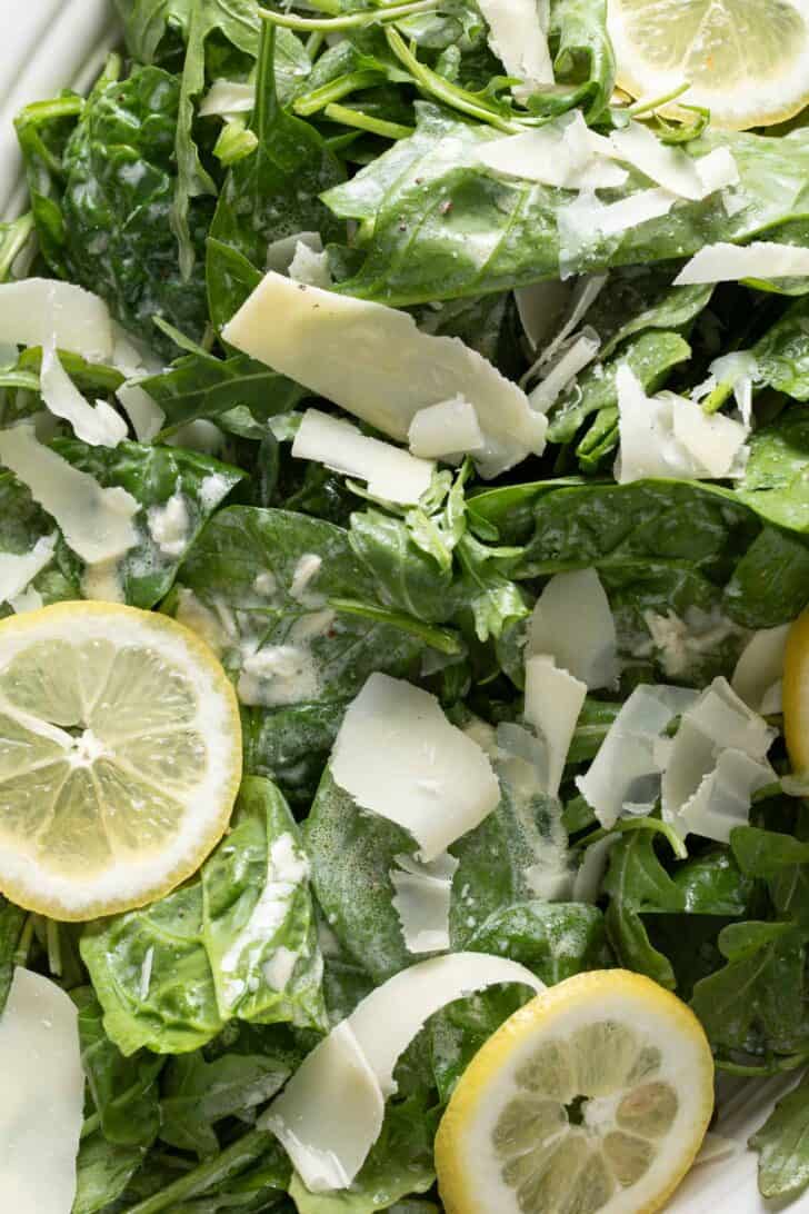 A close up photo of mixed greens with lemon slices.