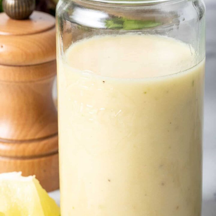 A clear glass mason jar filled with Lime Ginger Vinaigrette.