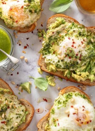 This Pesto Eggs Avocado Toast recipe is made with mashed avocado on your favorite toasted bread, topped with fried pesto eggs drizzled with honey. Avocado toast with egg is great for breakfast, lunch or as a light dinner! 