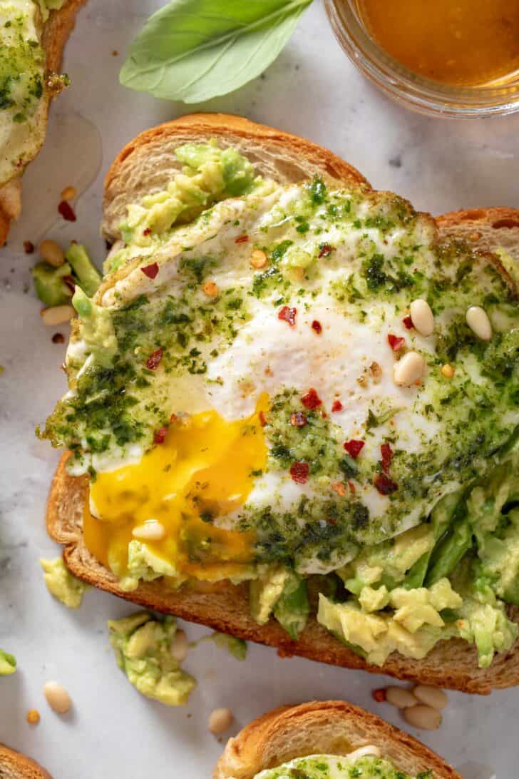 A piece of toast with a pesto egg on top.