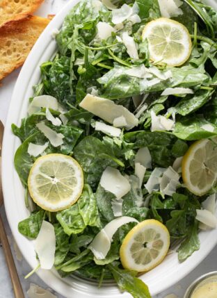 A white oval platter filled with Lemon Arugula Salad.