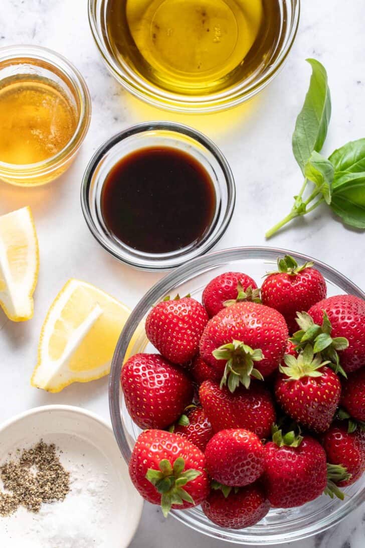 Four small clear glass bowls filled with fruit, balsamic vinegar, olive oil and honey.