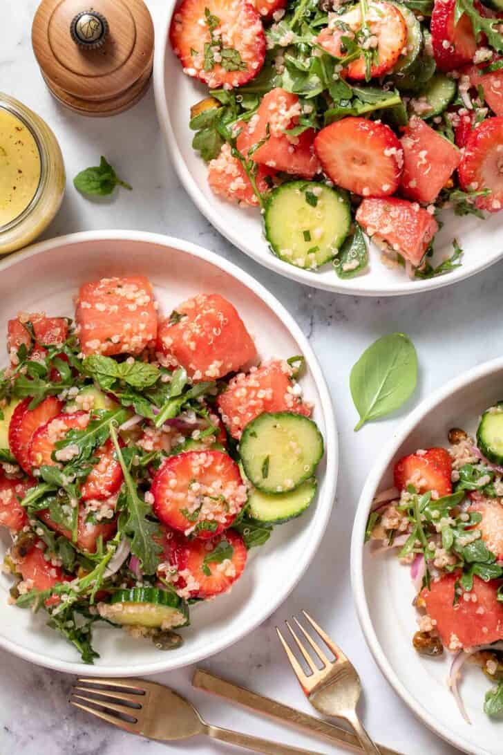 Three white plates filled with Watermelon Arugula Salad.