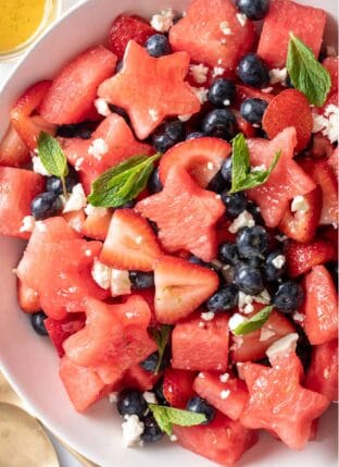 A white bowl filled with 4th of July Fruit Salad made with watermelon, strawberries, blueberries and Feta cheese.