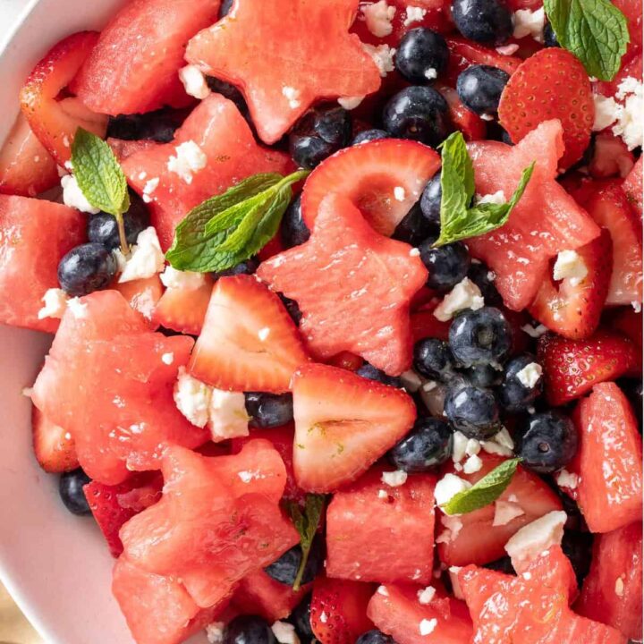 A white bowl filled with 4th of July Fruit Salad made with watermelon, strawberries, blueberries and Feta cheese.