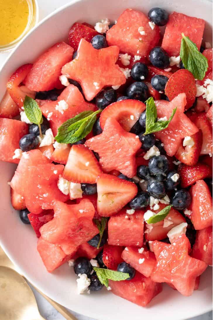 A white bowl filled with 4th of July Fruit Salad made with watermelon, strawberries, blueberries and feta cheese.