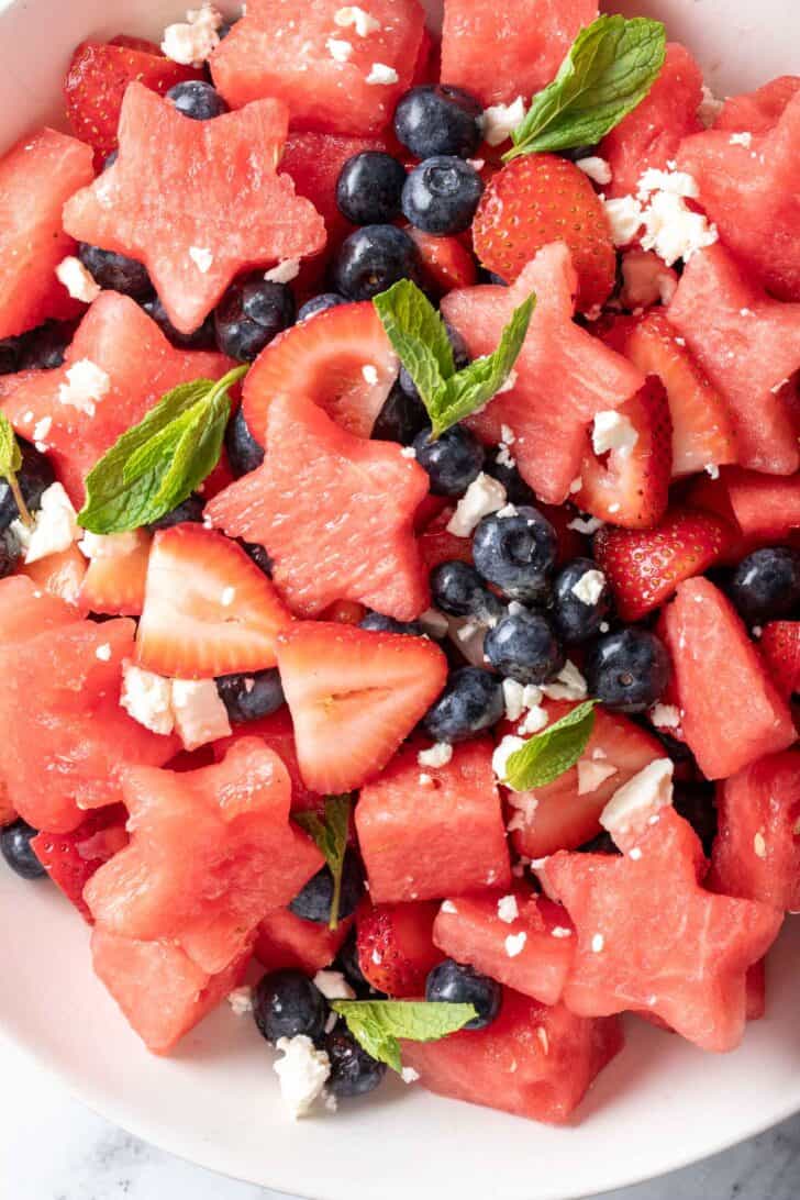 A white bowl filled with 4th of July Fruit Salad made with watermelon, strawberries, blueberries and Feta cheese.