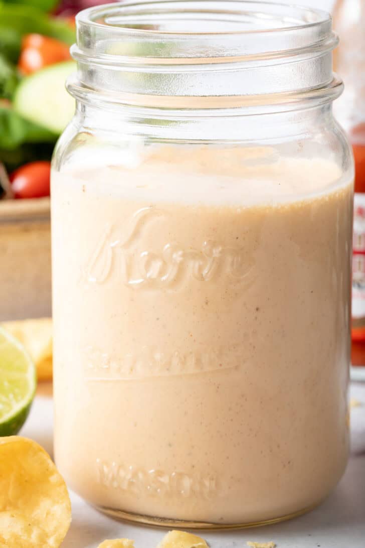 A clear glass mason jar filled with Buffalo Ranch Dressing. 