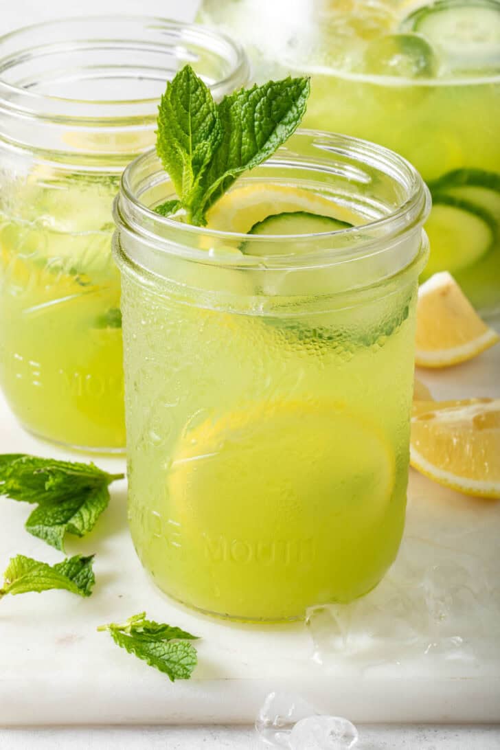 Two clear glass mason jars filled with Cucumber Lemonade.