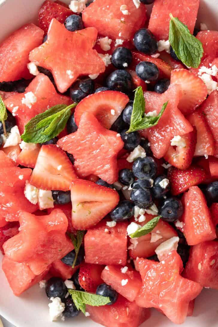 A white bowl filled with watermelon, strawberries and blueberries.