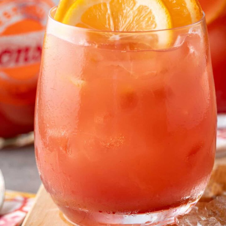 A clear drinking glass filled with Hawaiian Fruit Punch Juice made with papaya, mango, pineapple juice, cranberry juice and coconut water.