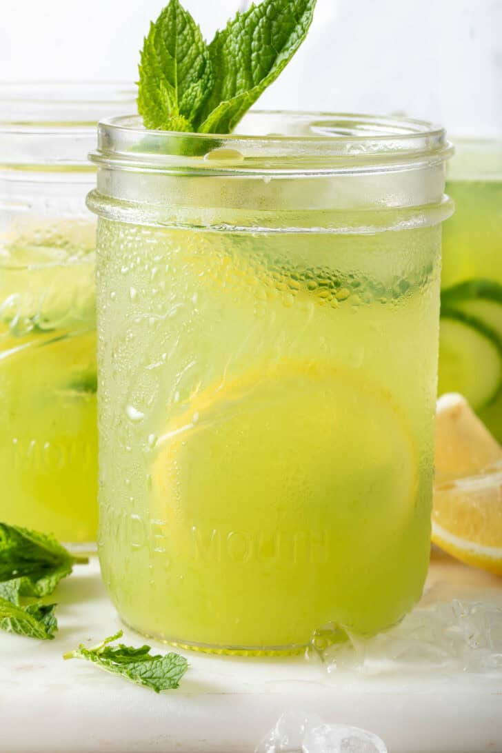 Two clear glass mason jars filled with Cucumber Lemonade.