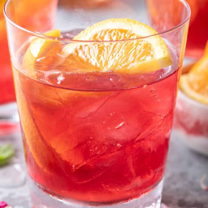 A clear drinking glass filled with Iced Cranberry Orange Green Tea.