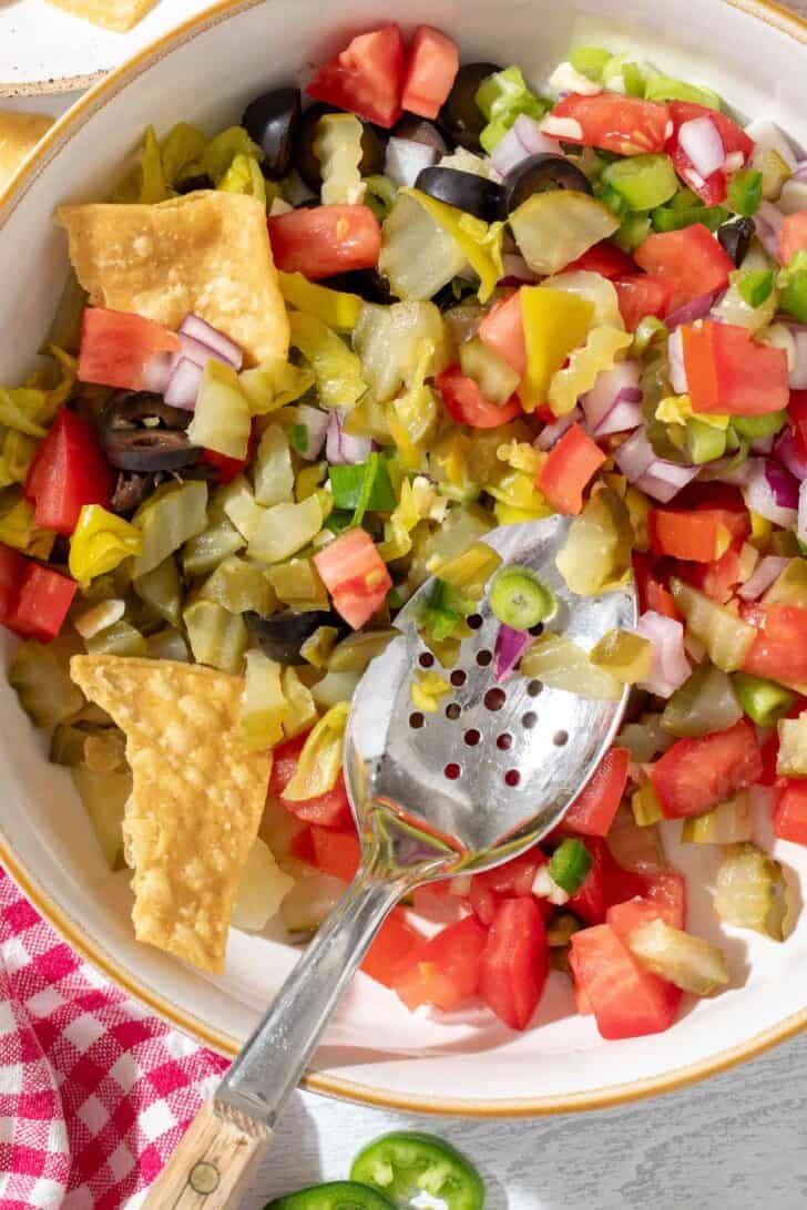 A white bowl filled with Pickle de Gallo. A spoon rests in the bowl.