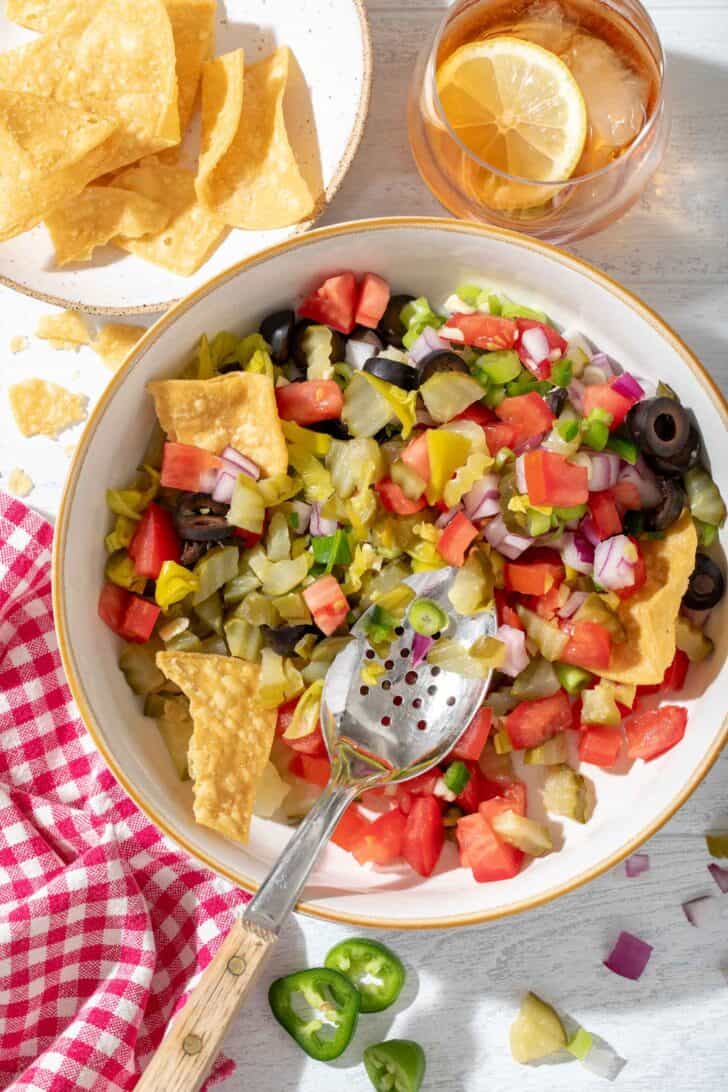 A white bowl filled with Pickled Pico de Gallo. A spoon rests in the bowl.