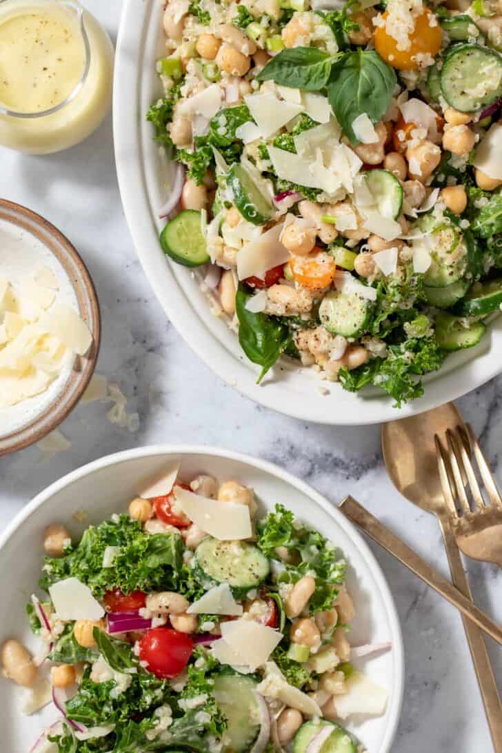 A white Platter filled with White Bean Quinoa Salad. A white plate filled with salad sits next to the platter.