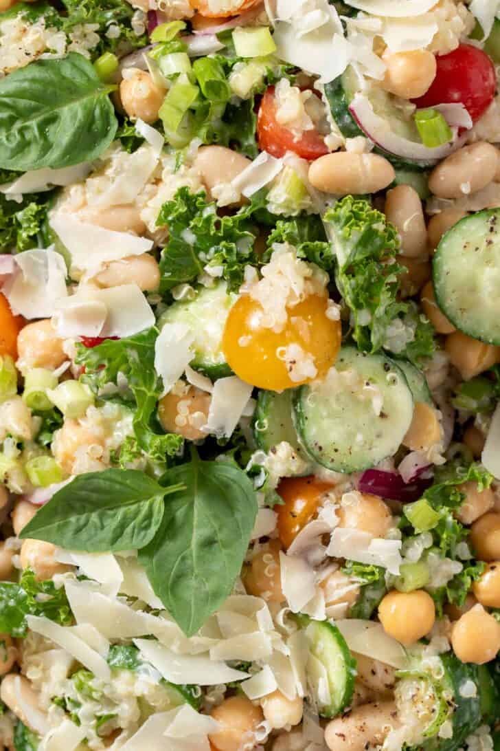 A white platter filled with White Bean Quinoa Salad made with curly kale, white beans, cucumber and tomatoes.