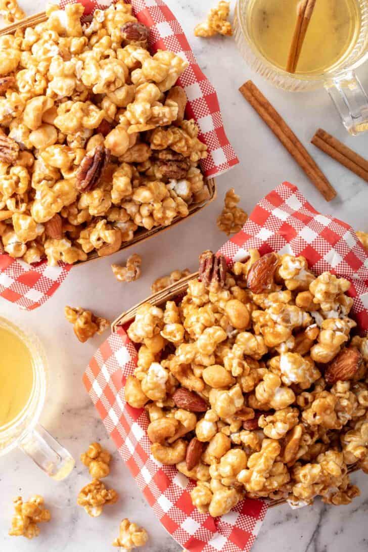 Two baskets lined with red and white checked paper filled with caramel popcorn.