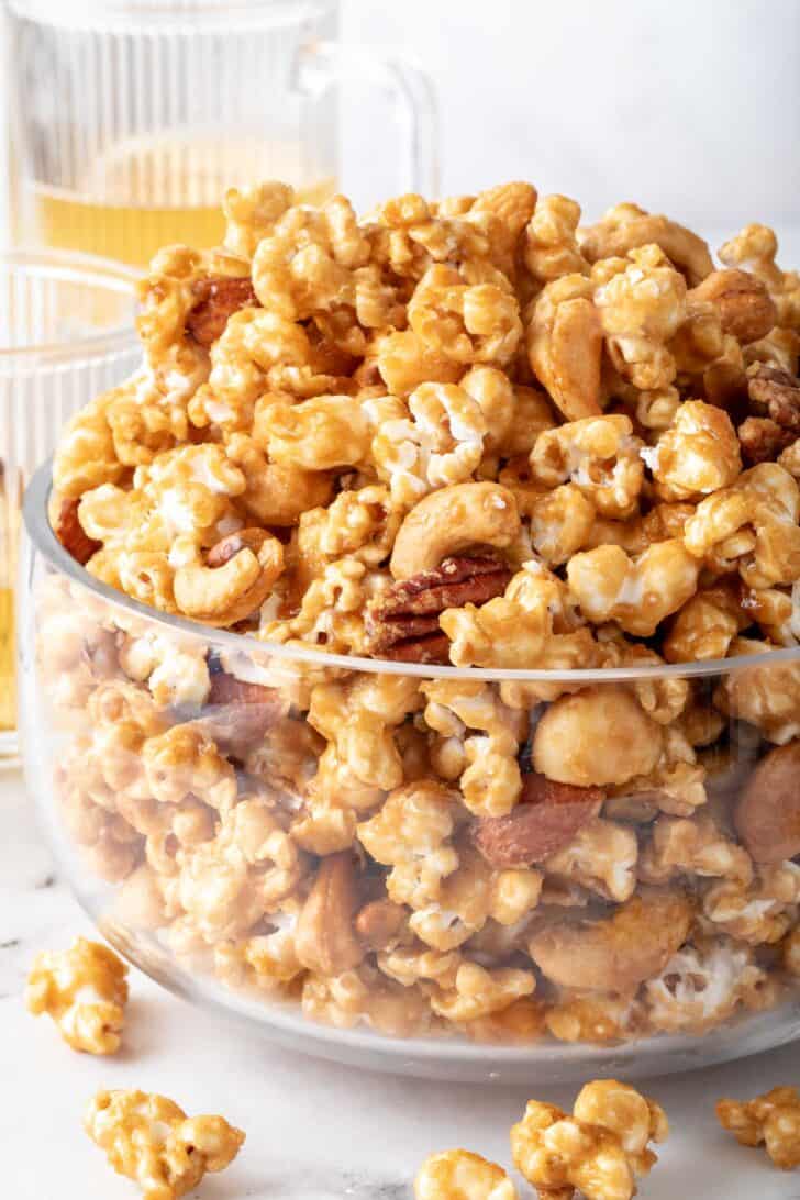 A clear glass bowl filled with Caramel Popcorn.