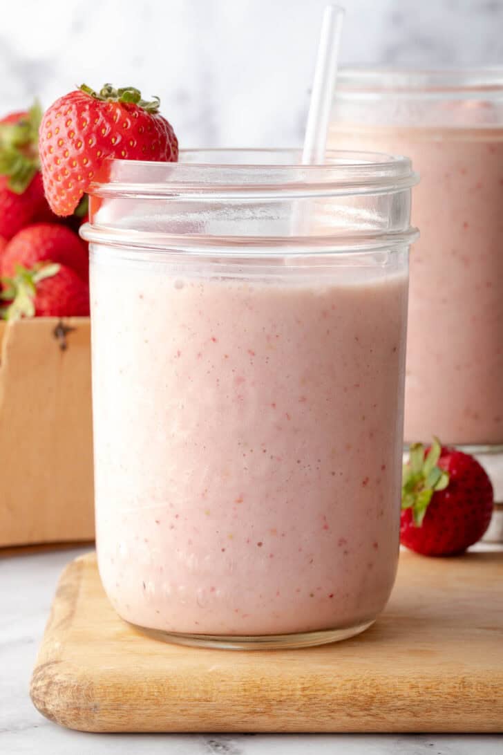 A clear glass mason jar filled with a fruit shake.