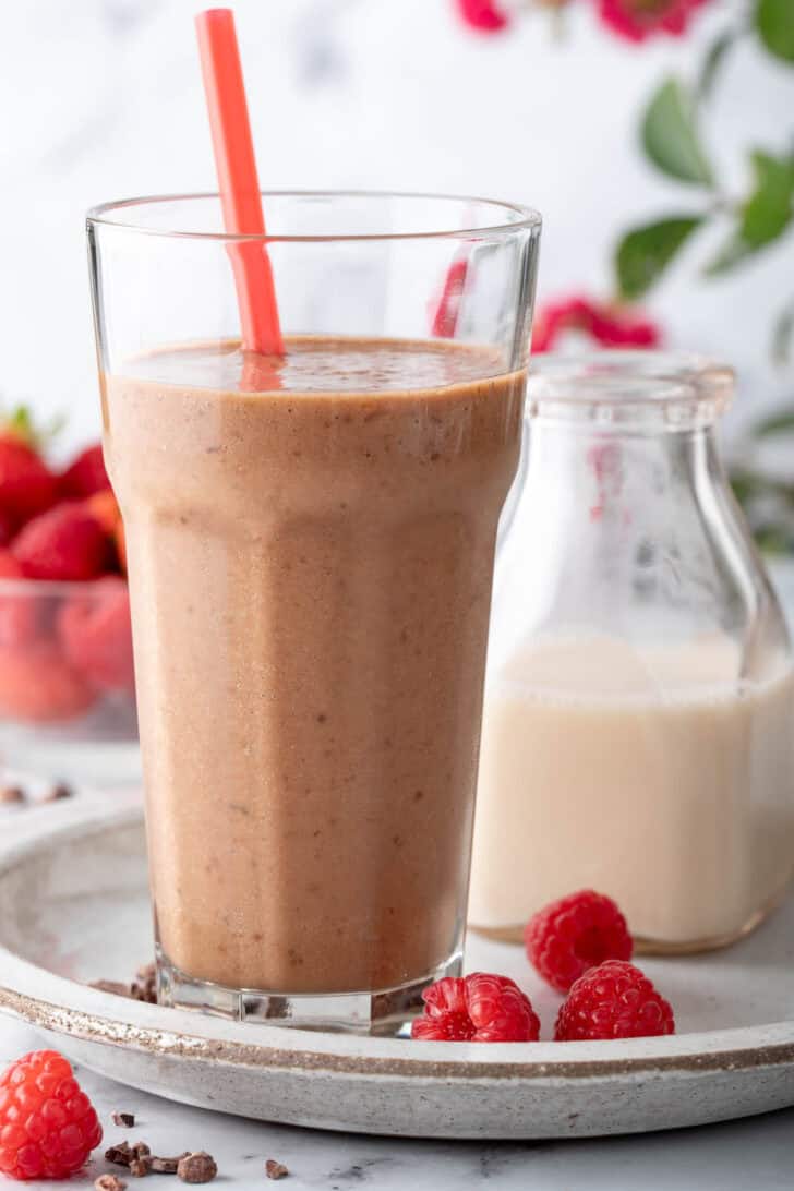 A clear drinking glass filled with Chocolate Banana Smoothie.