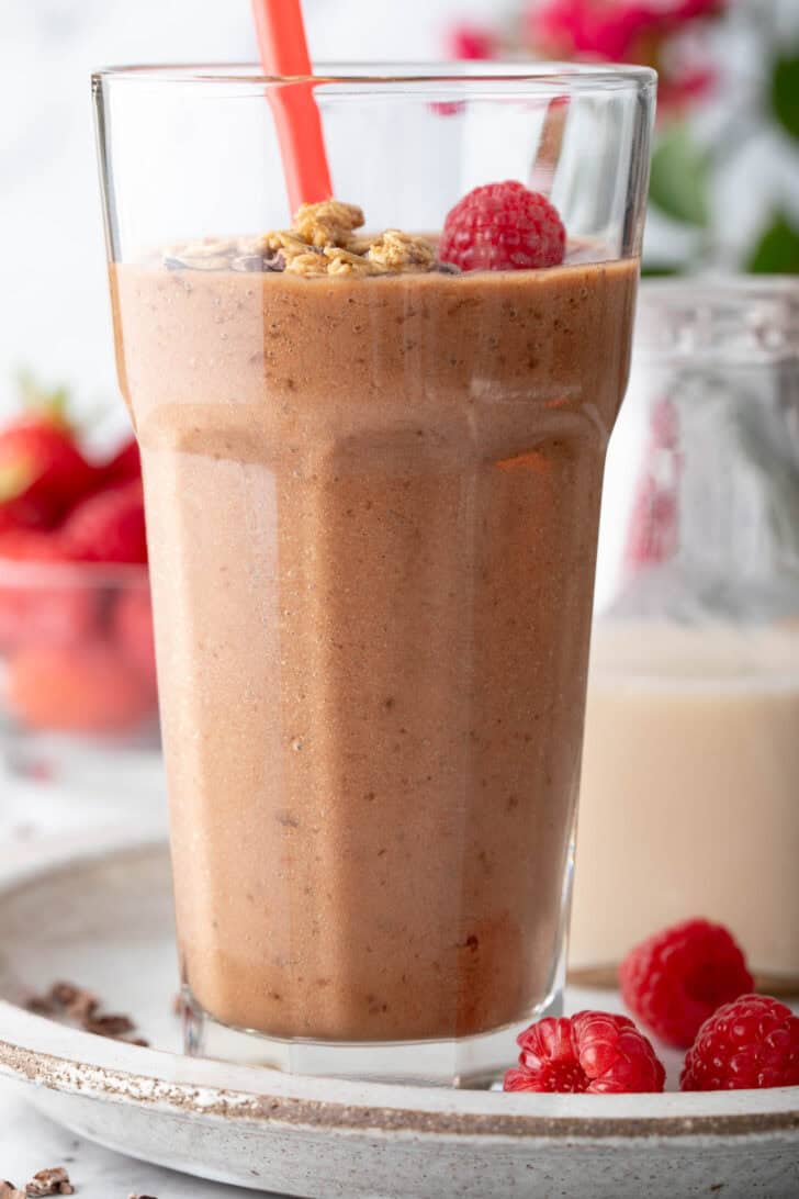 A clear drinking glass filled with Chocolate Banana Smoothie.