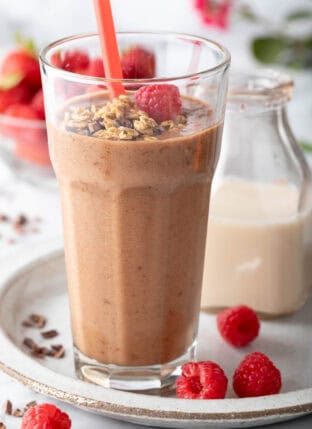 A clear drinking glass filled with Chocolate Banana Smoothie.