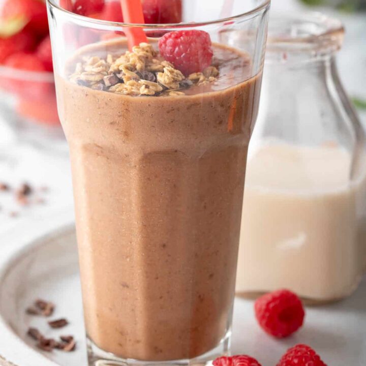 A clear drinking glass filled with Chocolate Banana Smoothie.