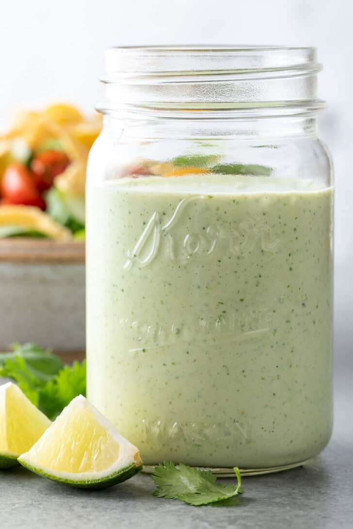 A clear glass mason jar filled with Cilantro Ranch Dressing.