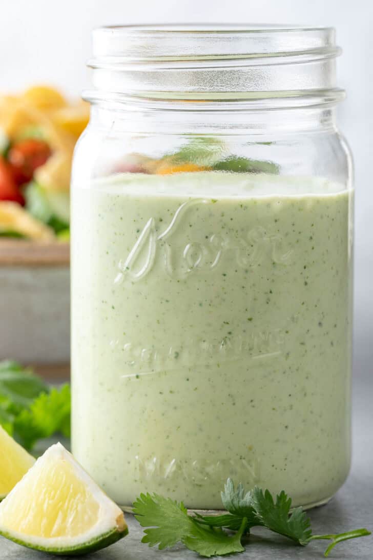 A clear glass mason jar filled with Cilantro Ranch Dressing.