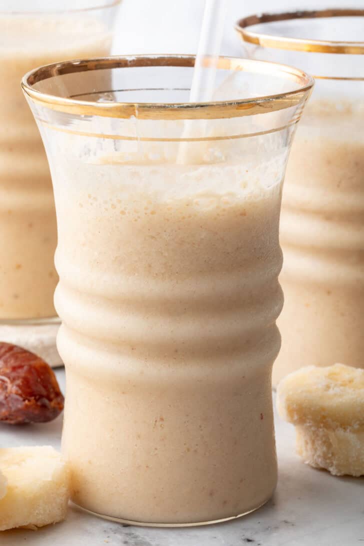 Three clear drinking glasses filled with a creamy smoothie.