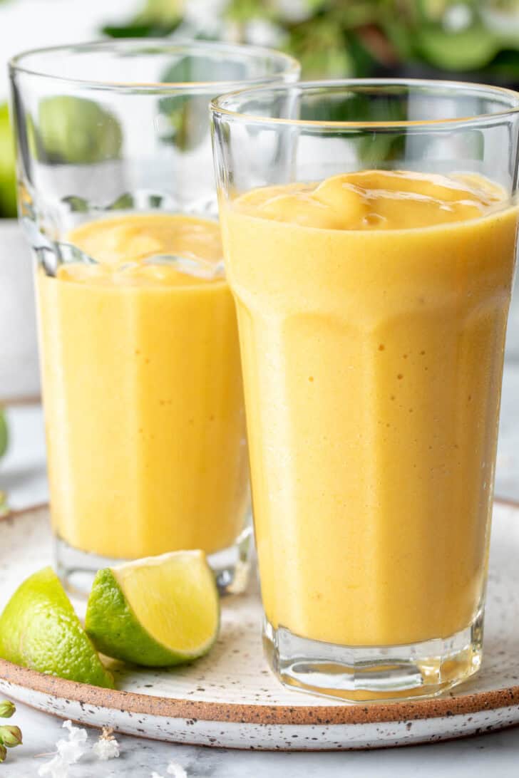 Two clear drinking glasses filled with pineapple Mango Smoothie.