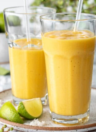 Two clear drinking glasses filled with pineapple Mango Smoothie.