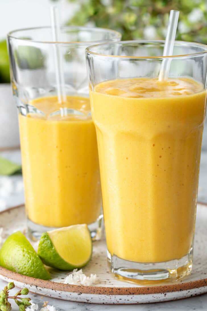 Two clear drinking glasses filled with pineapple Mango Smoothie.