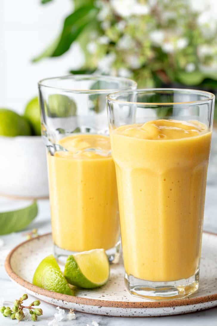 Two clear drinking glasses filled with fruit shake.