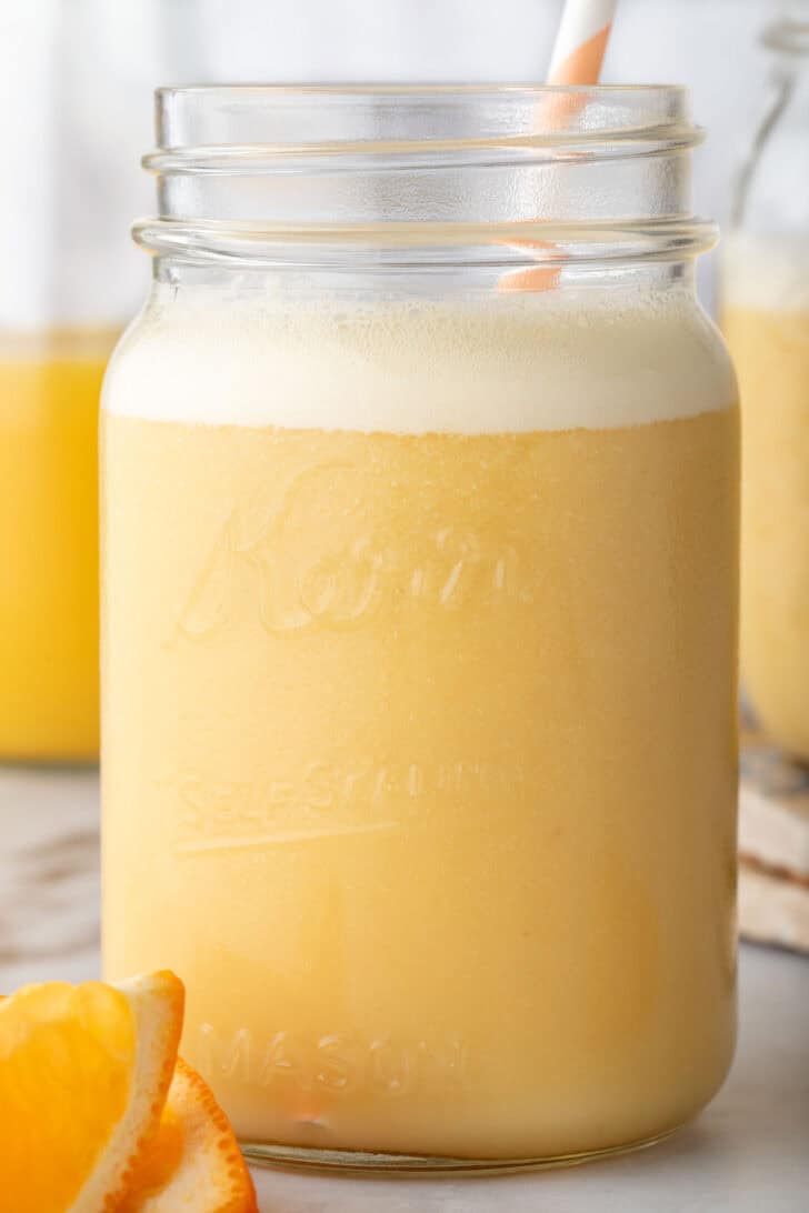 A clear mason jar filled with Orange Smoothie. 