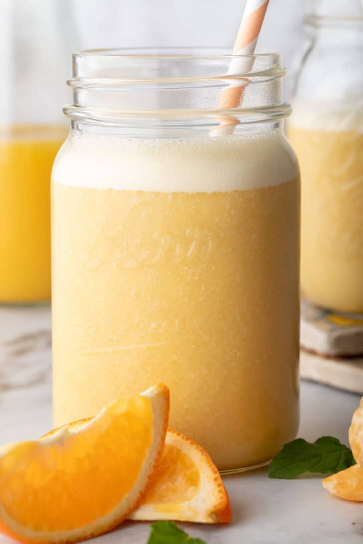 A clear mason jar filled with a citrus shake.