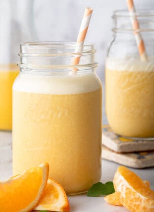 Two clear mason jars filled with Orange Juice Smoothie.