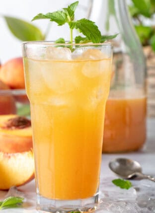 A clear drinking glass filled with Peach Green Tea.