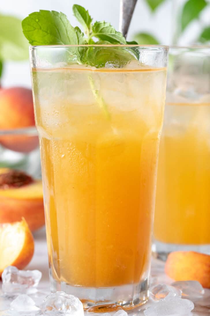 Two drinking glasses filled with Peach Green Tea.