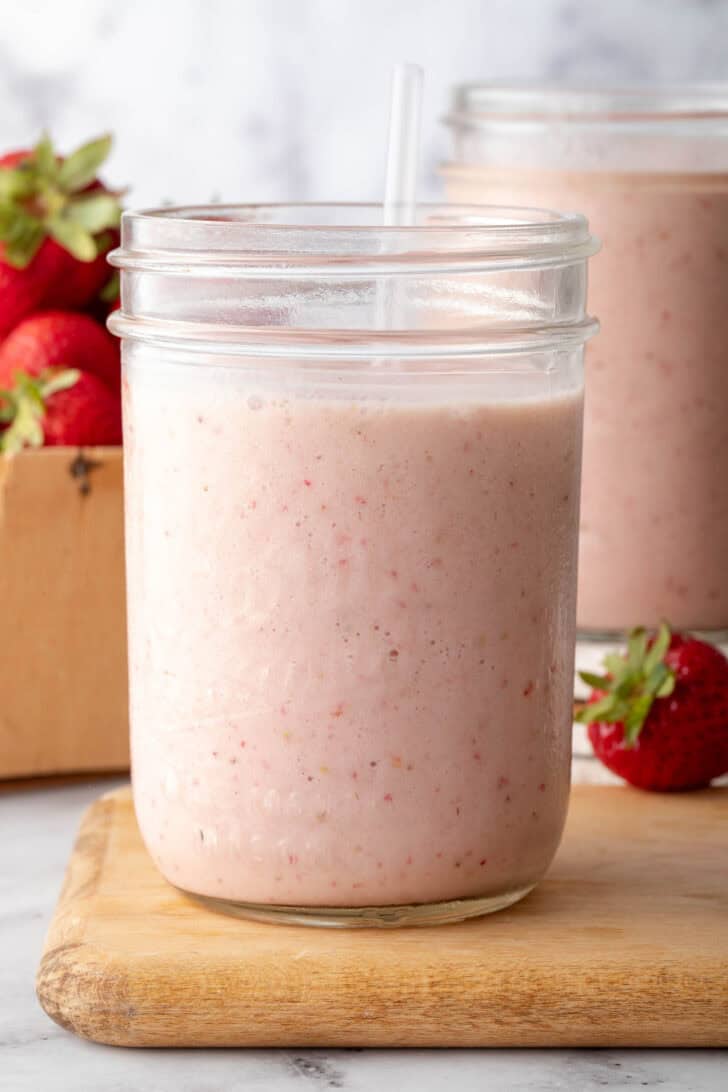 A clear glass mason jar filled with Strawberry Banana Smoothie.