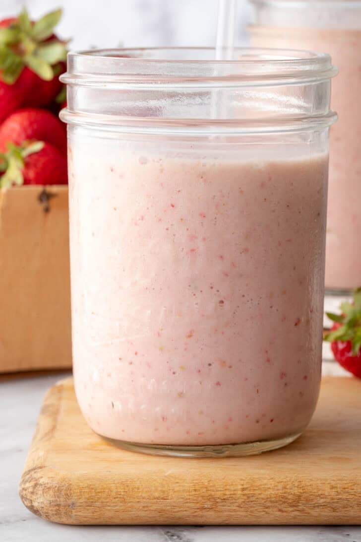 A clear drinking glass filled with Strawberry Banana Smoothie.