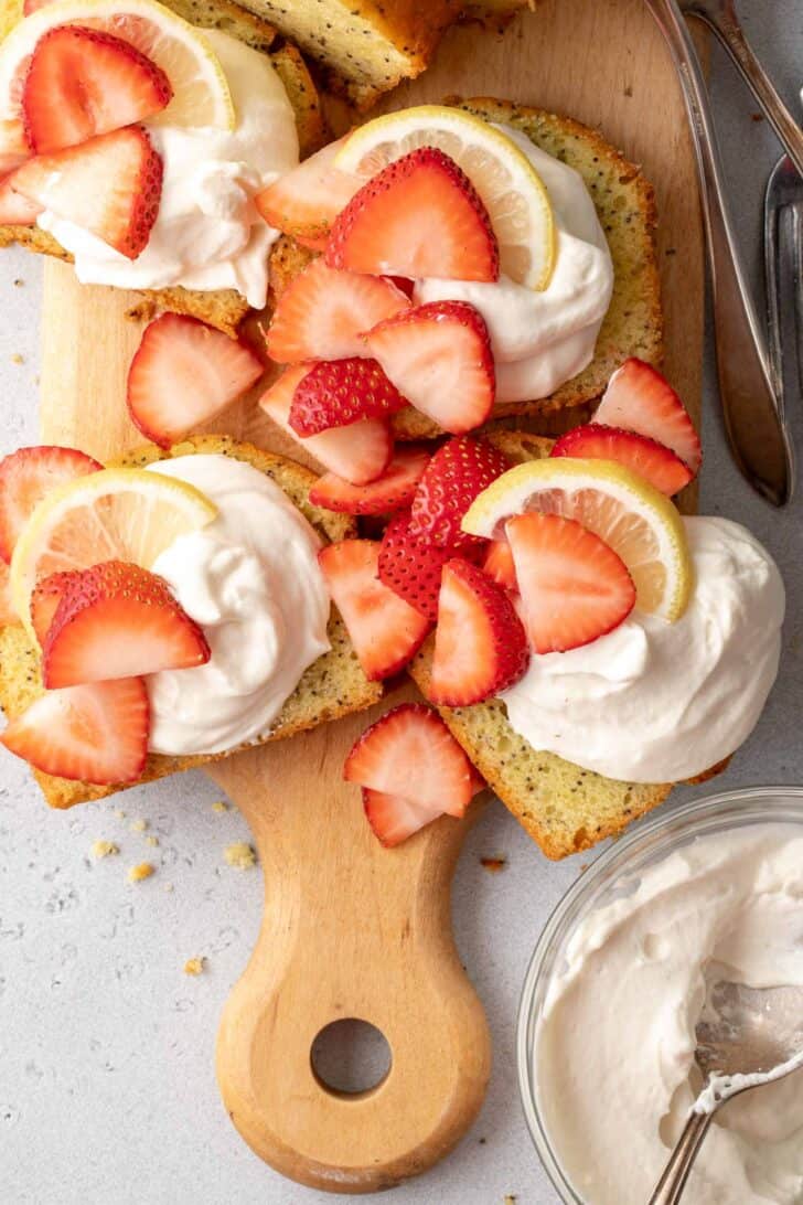 Slices of pound cake topped with dollops of Mascarpone Whipped Cream and garnished with slices of strawberries.