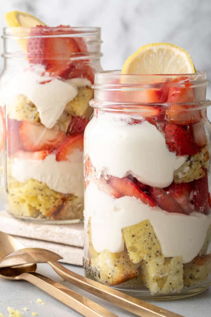 Two mason jar parfaits filled with pieces of pound cake and strawberries.