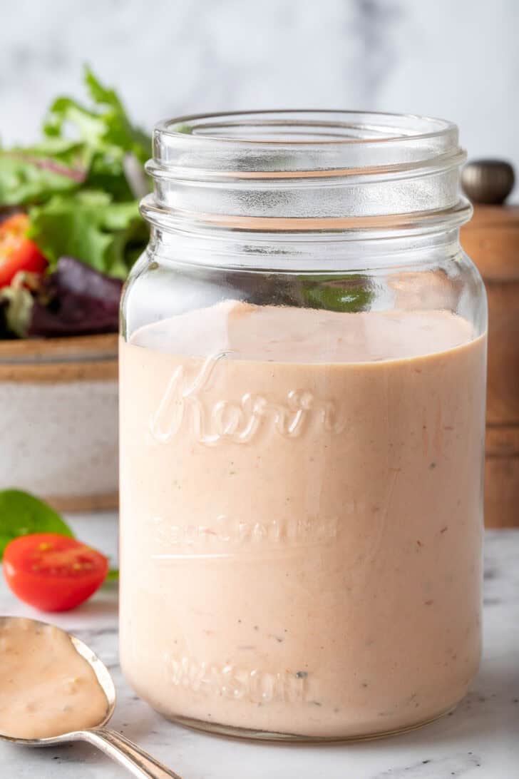 A clear glass mason jar filled with a creamy sauce.