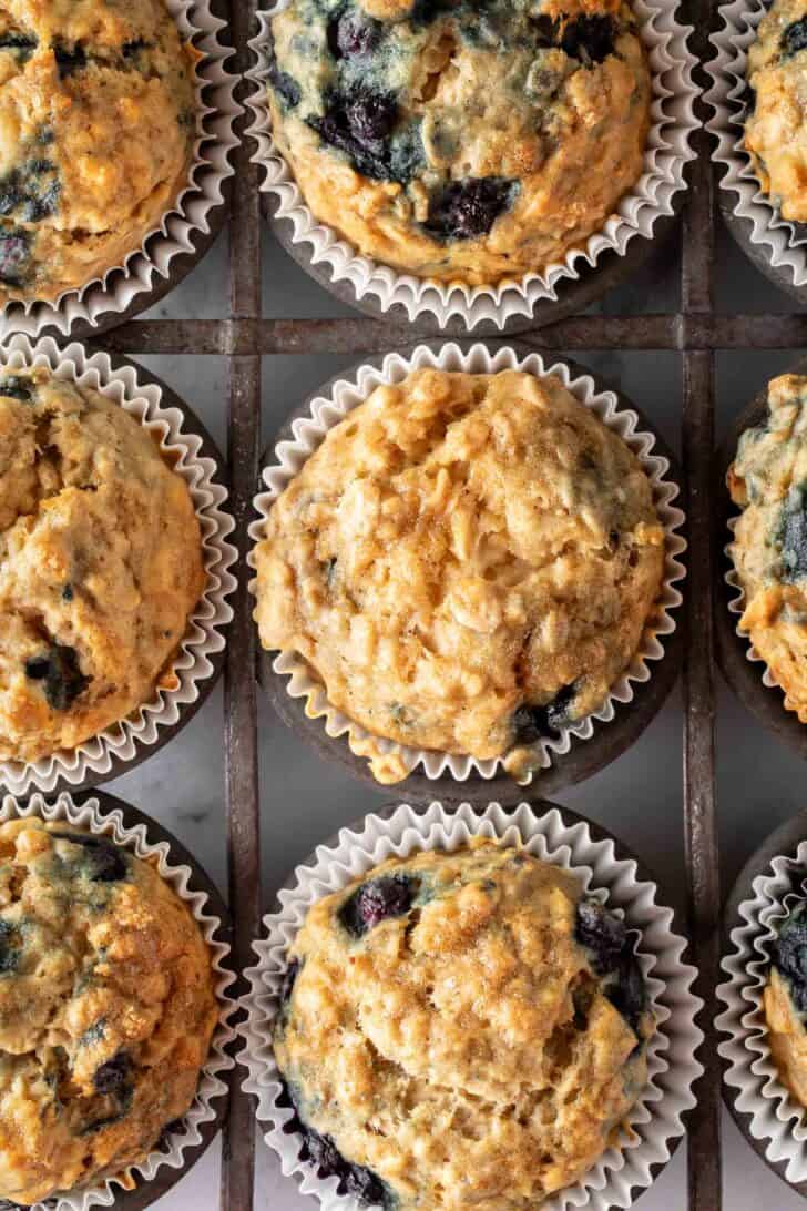 A metal muffin tin filled with blueberry oat muffins.